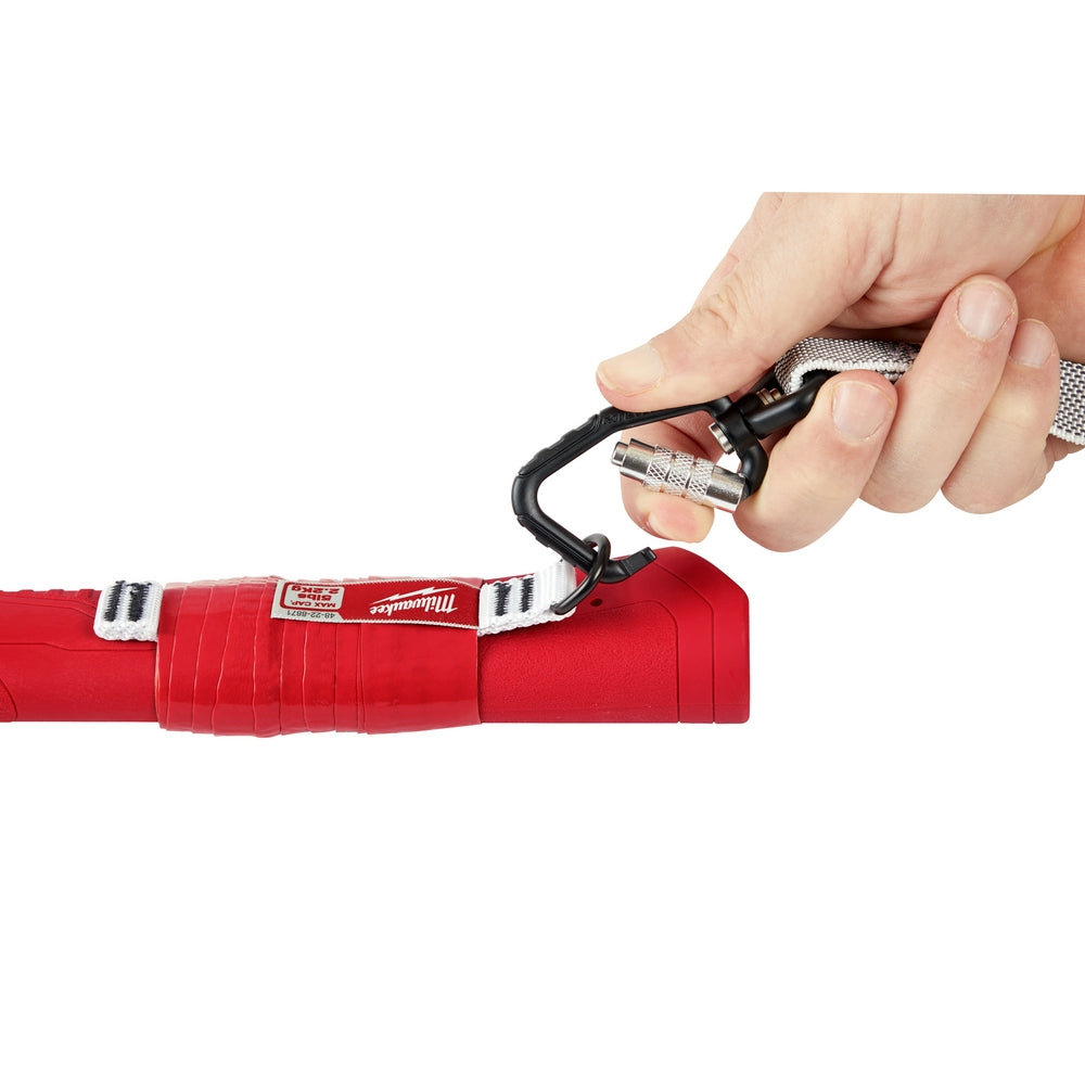 Hand holding a red tool with a black handle on a white background