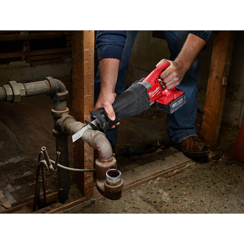 Person using a power tool on a pipe in a basement.