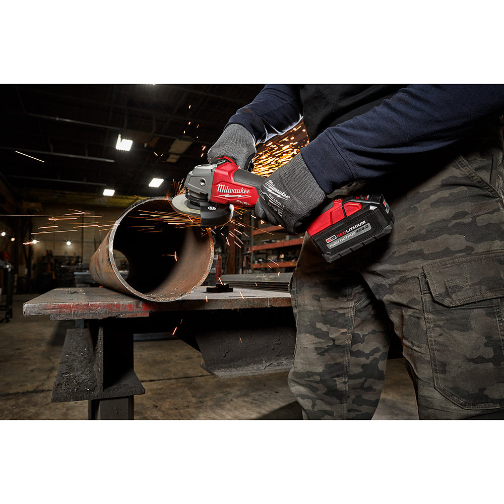 Person using a grinder to cut a metal pipe in a workshop.