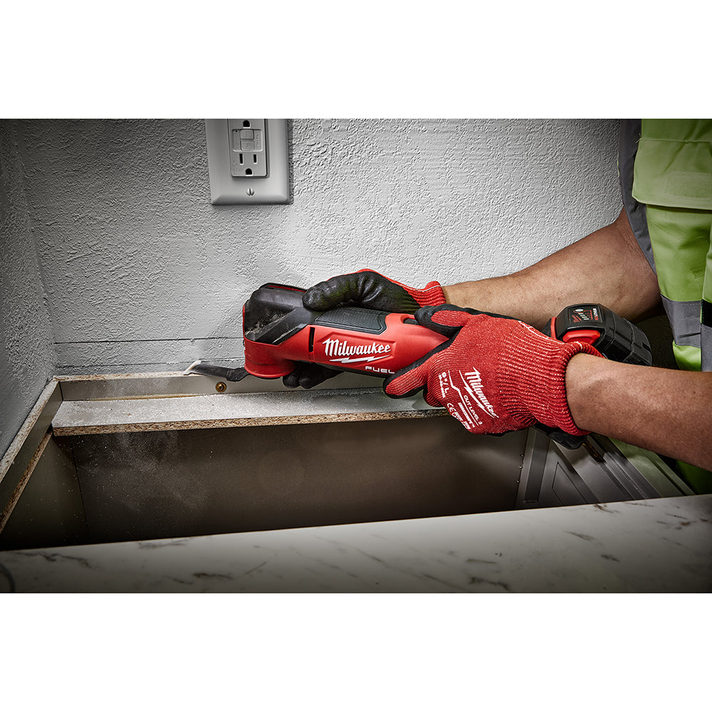 Person using a M18 FUEL™ Oscillating Multi-Tool on a metal surface with a wall outlet in the background.