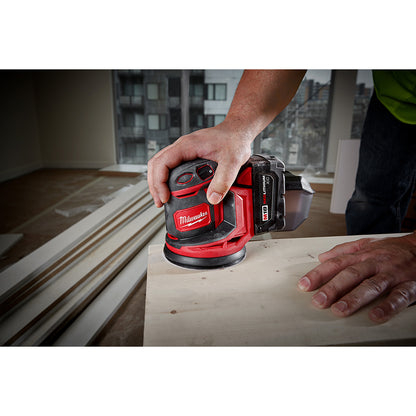 Person using a M18™ Random Orbit Sander on a wooden surface.