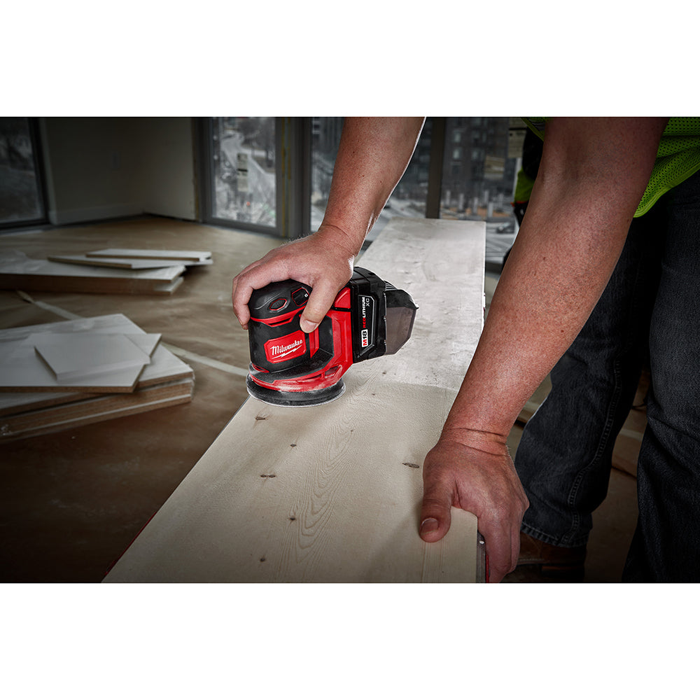 Person using a M18™ Random Orbit Sander on a wooden surface.