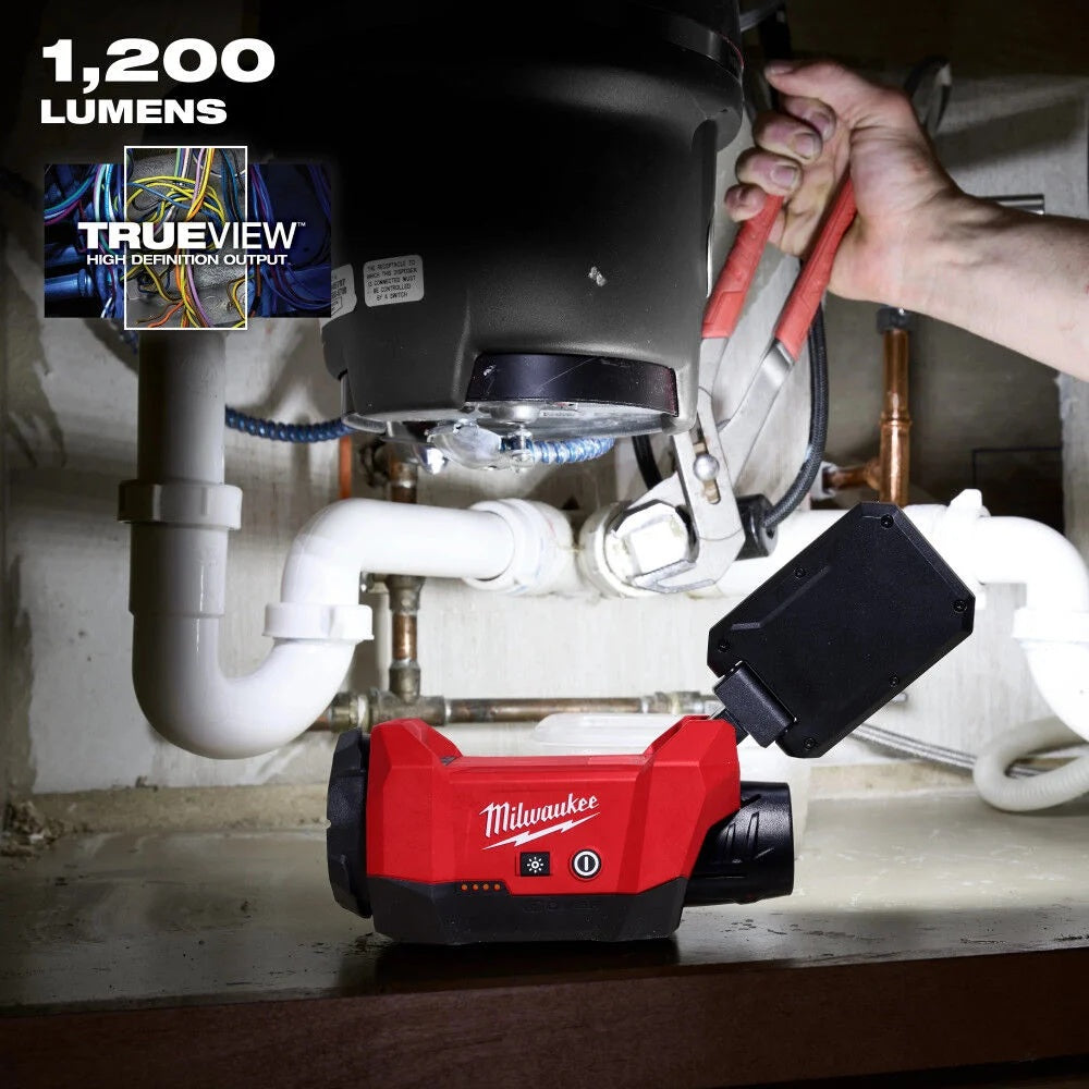 Milwaukee tool with a light illuminating a plumbing repair under a sink.