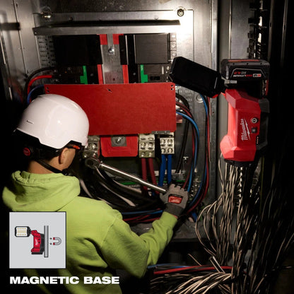 Person working on electrical panel with a tool, wearing a green jacket and white helmet. M12 light in the background.