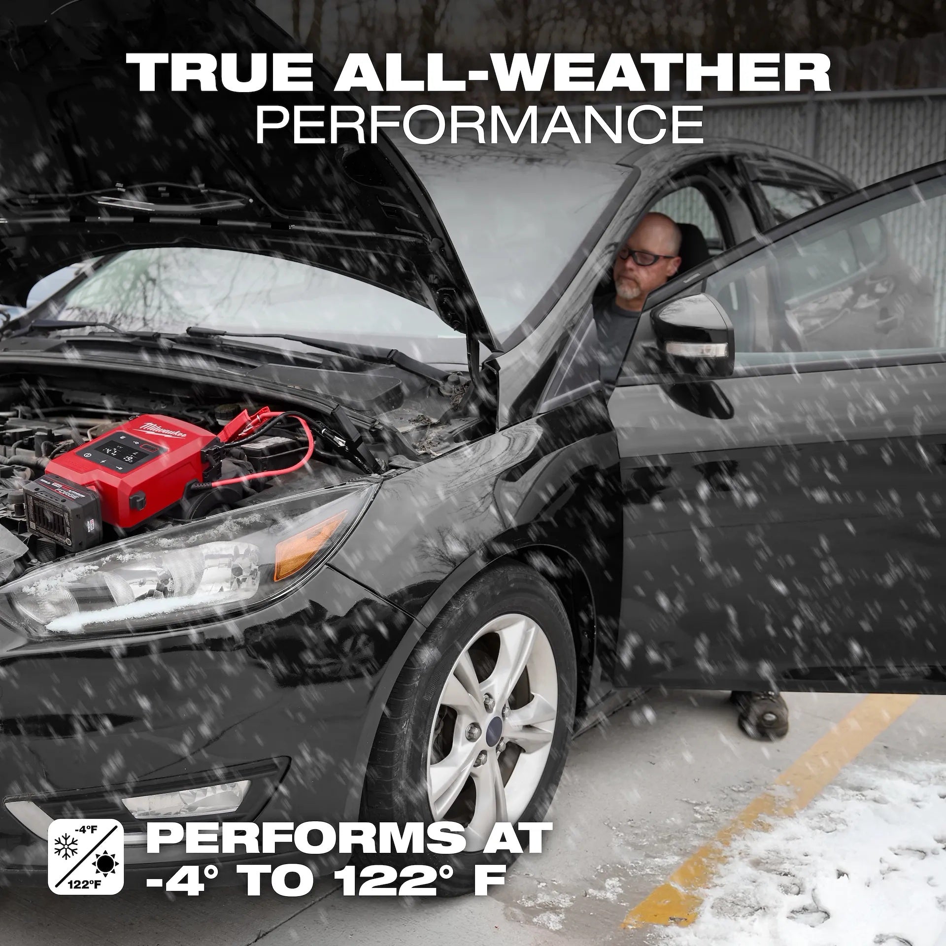 Person checking car engine with a jump starter in the snow, emphasizing 'True All-Weather Performance'.