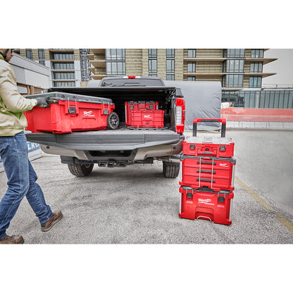 Person loading PACKOUT™ 3-Drawer Tool Box into the back of a truck in an urban setting.