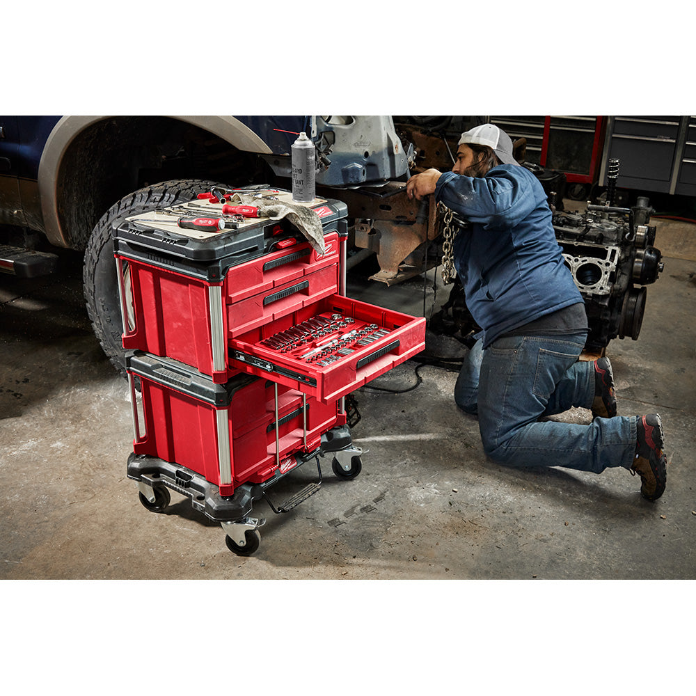 Mechanic using a PACKOUT™ 3-Drawer Tool Box in a garage setting.